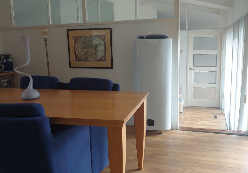 Woonkamer met een witte cilindrische kachel naast de eettafel